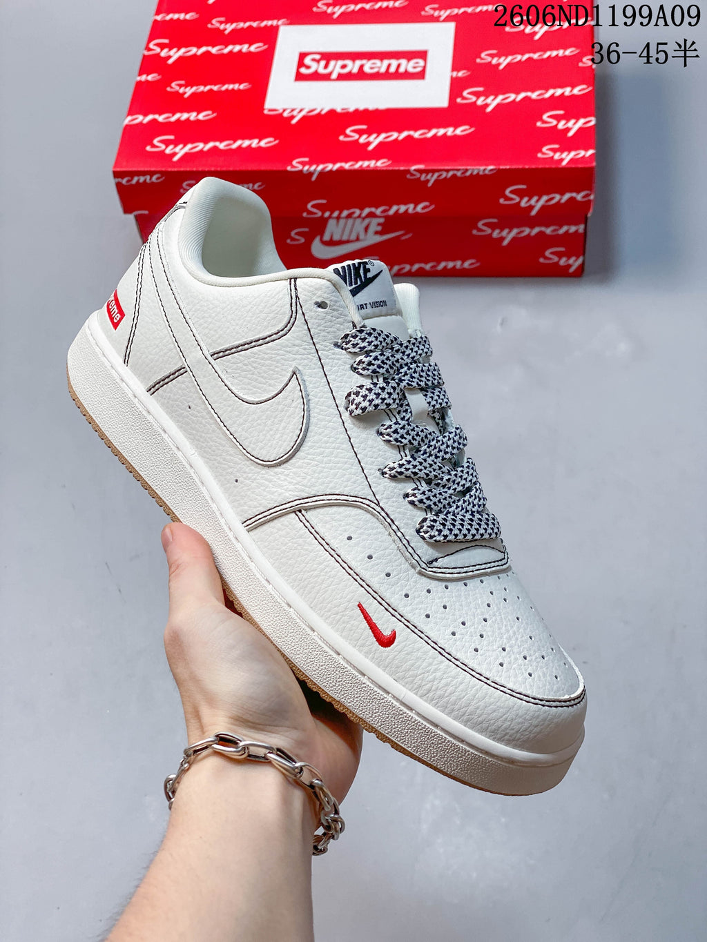 Angled view of the white low-top sneaker with small red Swoosh detail and patterned laces.