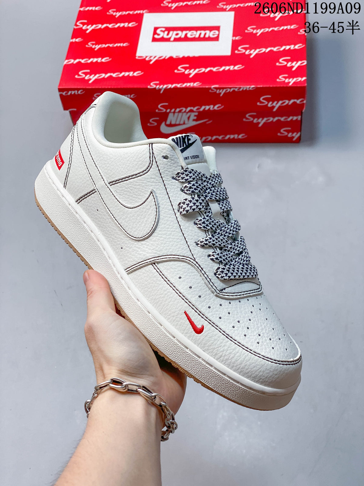 Angled view of the white low-top sneaker with small red Swoosh detail and patterned laces.