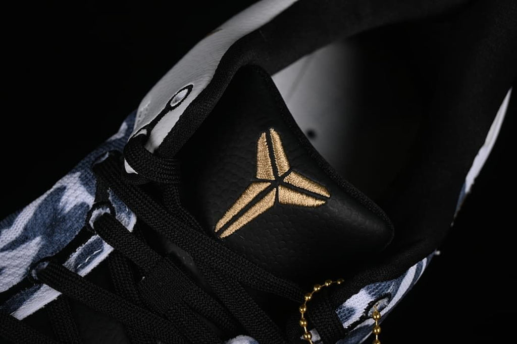 Close-up of the black tongue with a gold Kobe logo and black laces.