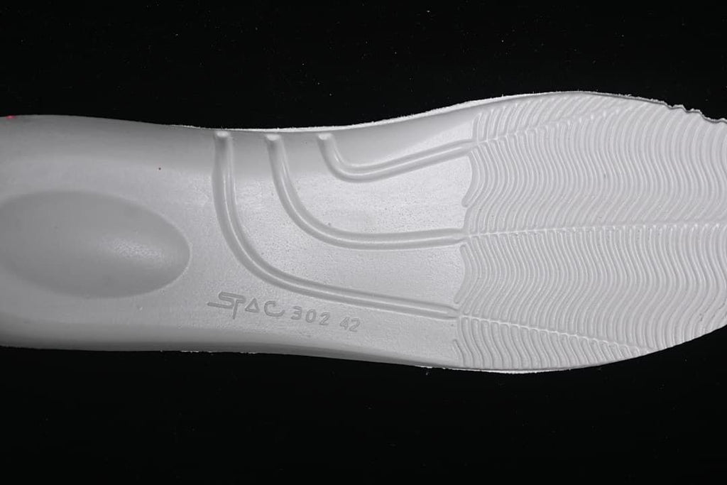 Close-up of the white sneaker outsole and its molded tread.