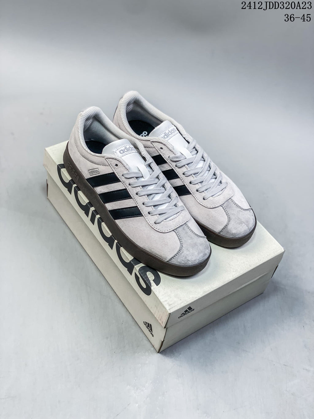 Pair of light grey Adidas VL Court Classic sneakers with dark stripes and gum-toned soles