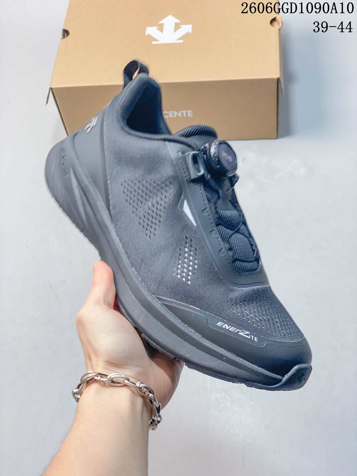 Angled side view of a dark gray Descente sneaker showing the dial closure and ENERZITE forefoot lettering; image text lists sizes 39–44.