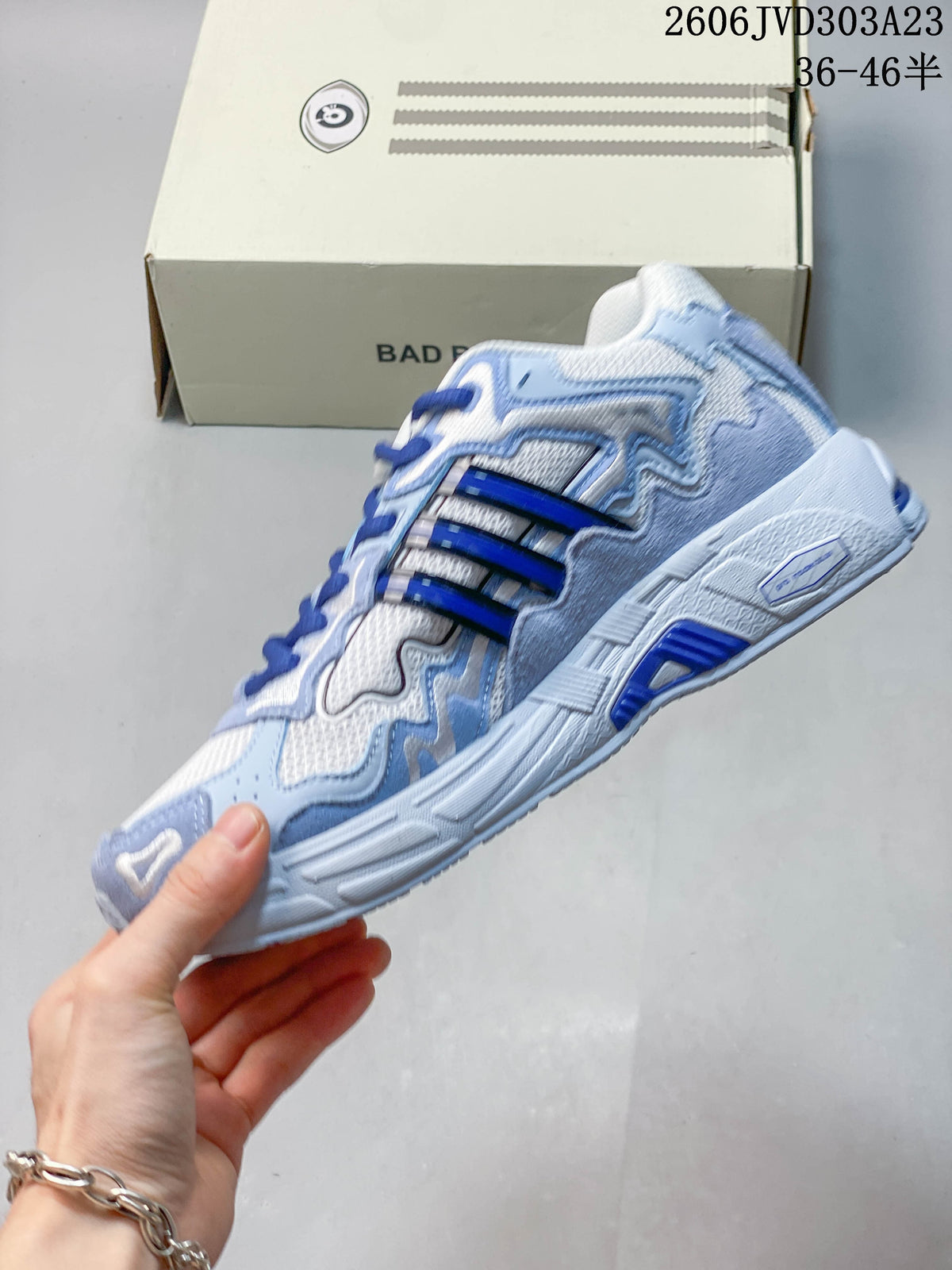 Side profile showing layered blue panels, three stripes, and a sculpted sole