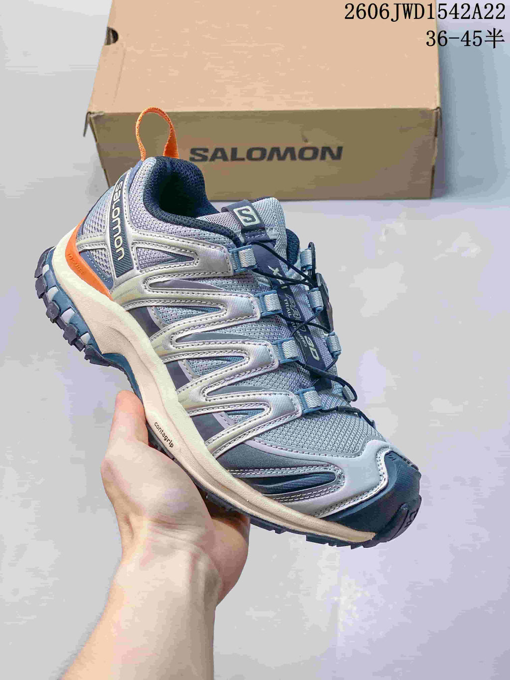 Blue-gray Salomon trail-style sneaker with orange heel accent and quick-pull laces.