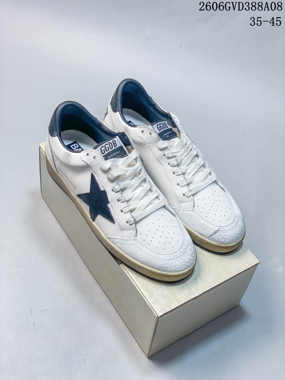 Pair of white Golden Goose Super-Star style sneakers with navy stars and distressed-look detailing
