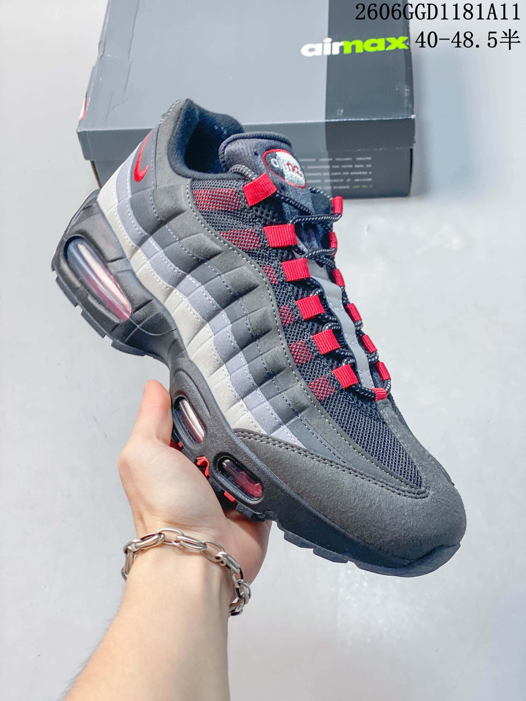 Angled side view highlighting the layered grey panels, red details, and visible sole cushioning