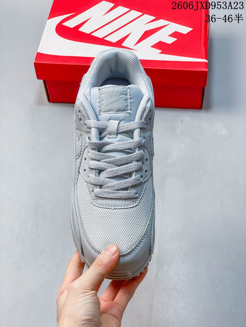 Top view of the laces and mesh-look toe section on a light grey Nike Air Max 90 sneaker