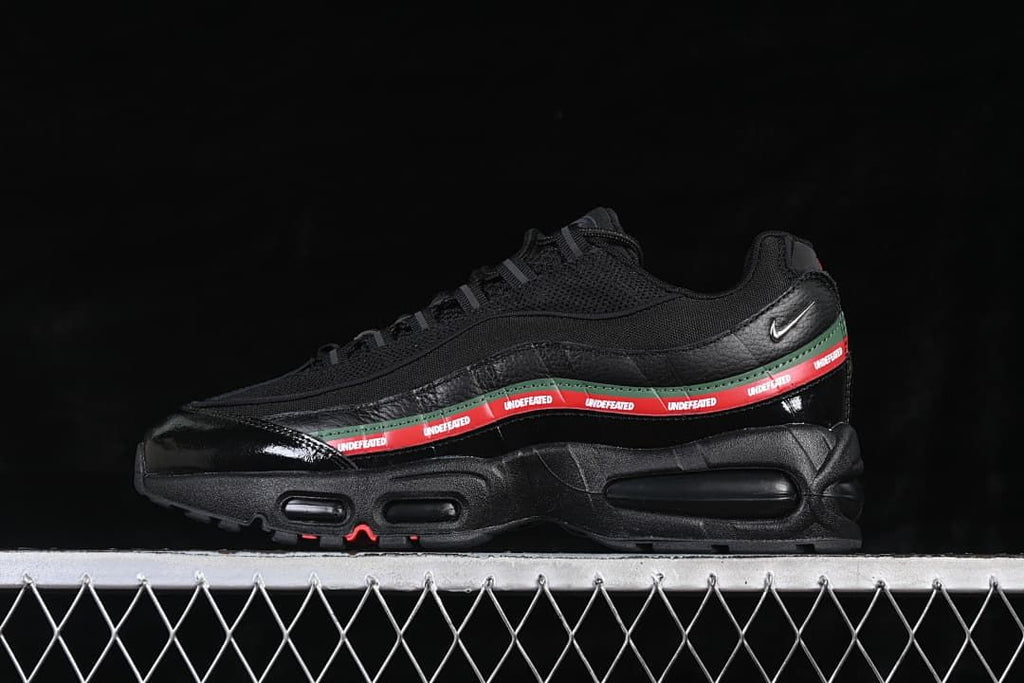 Side view of a black Nike Air Max 95 SP with red-and-green Undefeated side detailing