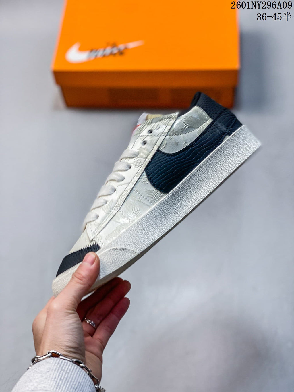 Side view of the low-top sneaker showing patterned cream panels and a large black Swoosh