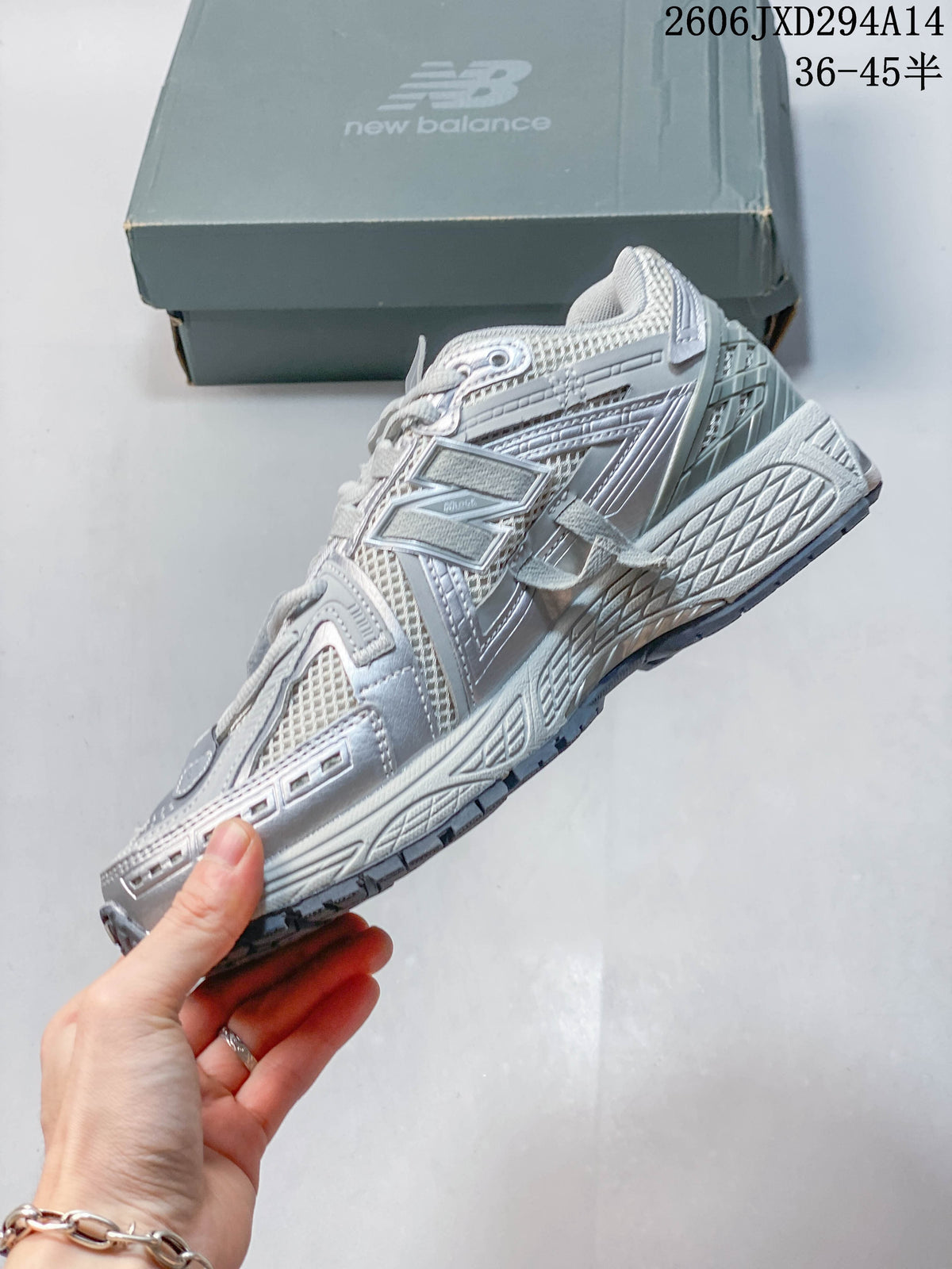 Side profile showing the layered upper and sole of a silver-grey New Balance 1906 sneaker.