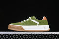 Side view of a green and white low-top lace-up sneaker with a tan outsole