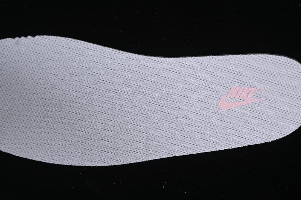Close-up view of a light-colored insole with a pink Nike logo.