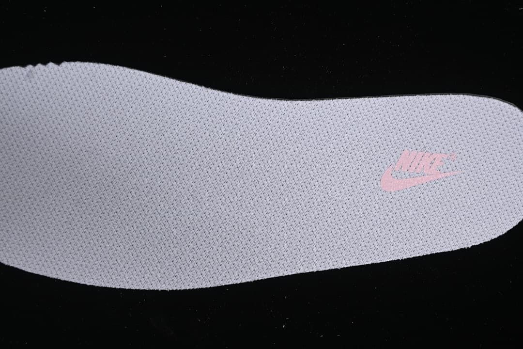 Close-up view of a light-colored insole with a pink Nike logo.