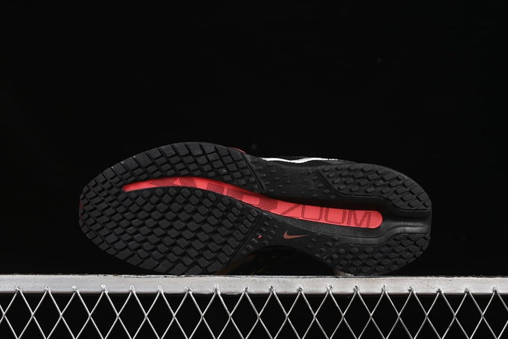 Outsole view with black tread and coral center detail