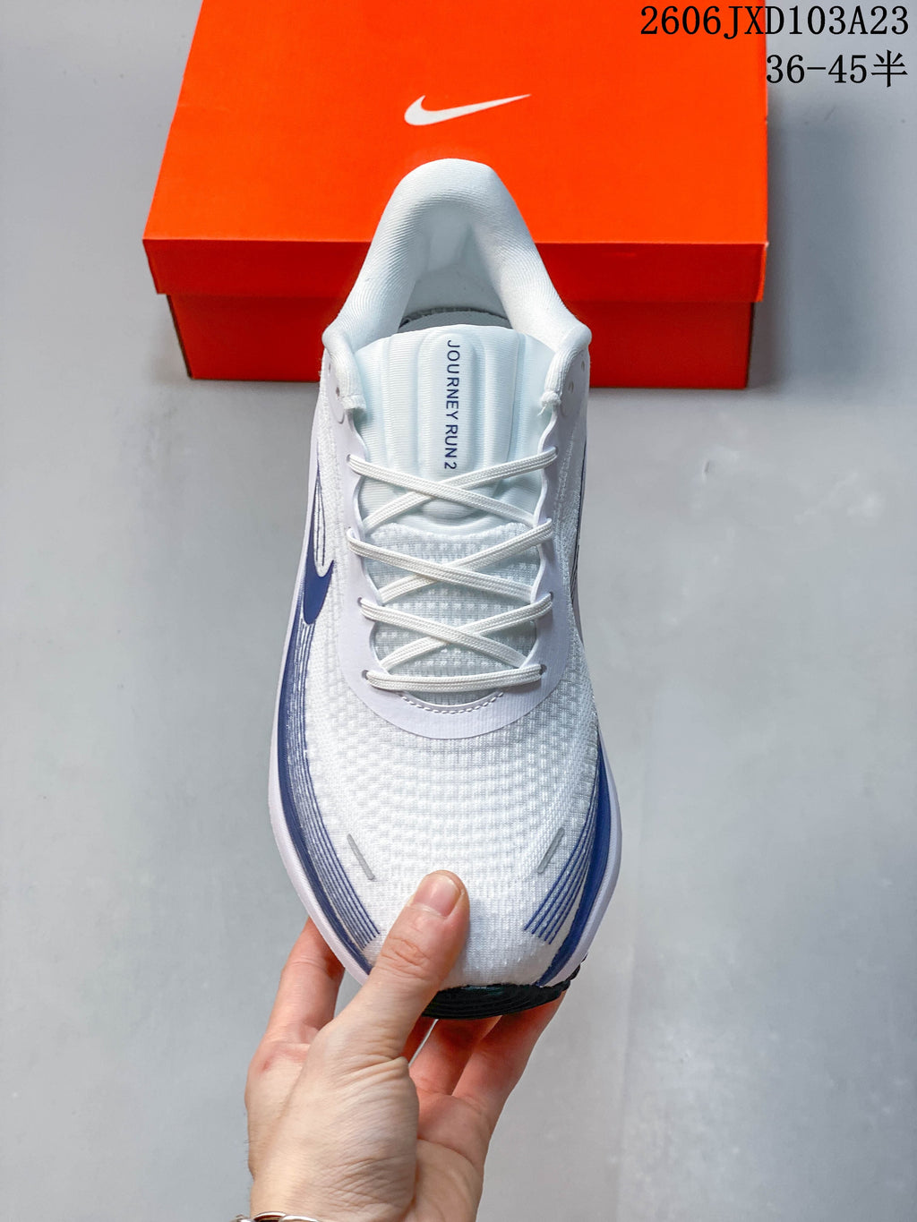 Top view of a white running shoe with laces and dark blue side graphics