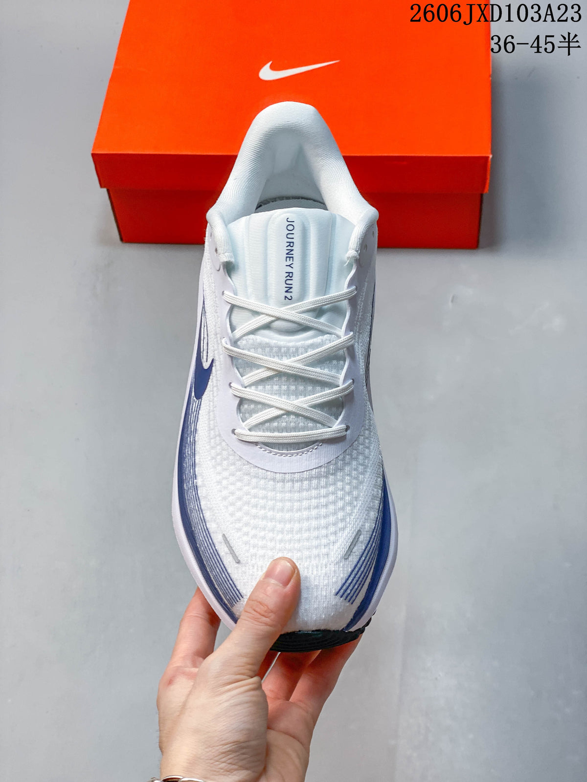 Top view of a white running shoe with laces and dark blue side graphics