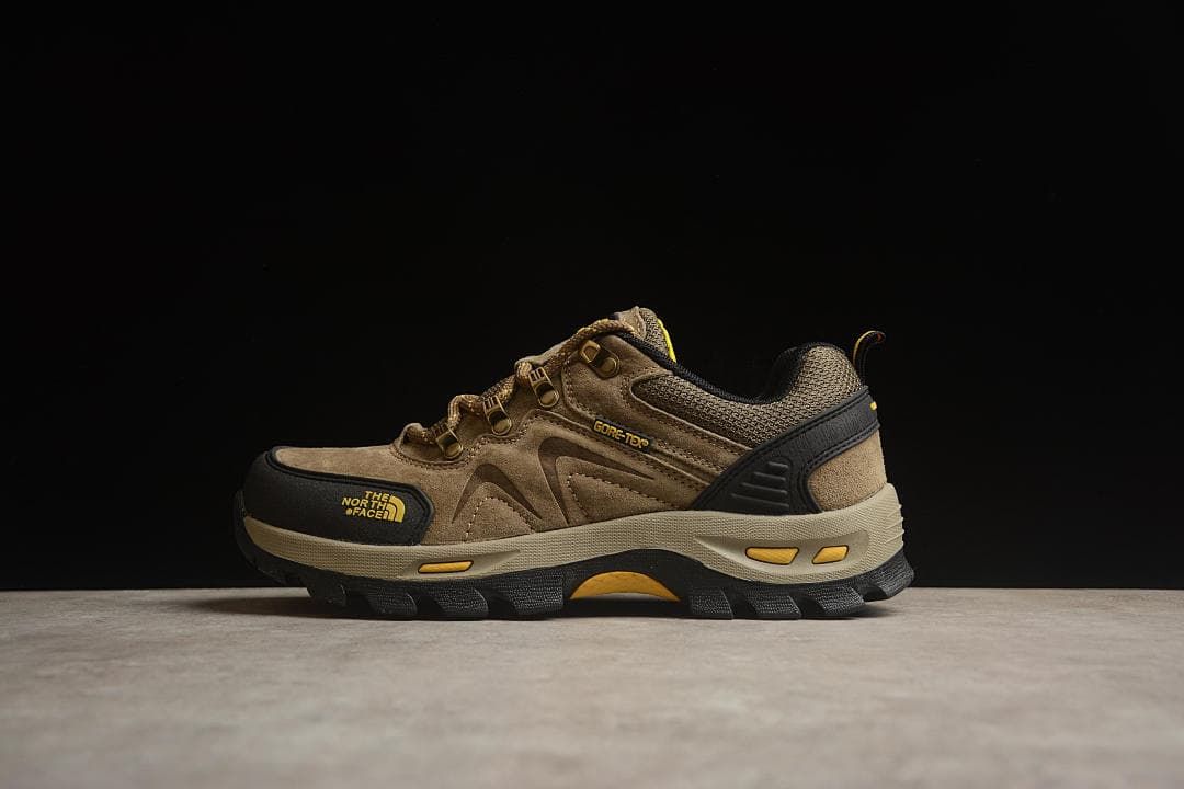 Side profile of a sand-colored shoe with black toe overlay and yellow accents