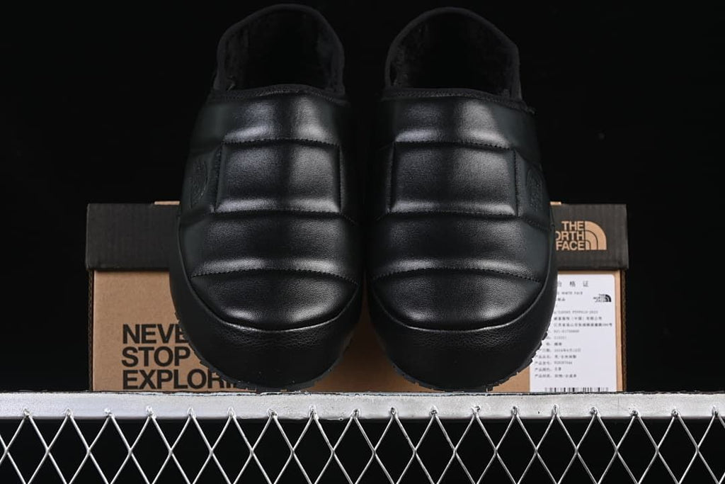 Pair of black mules shown from the front.