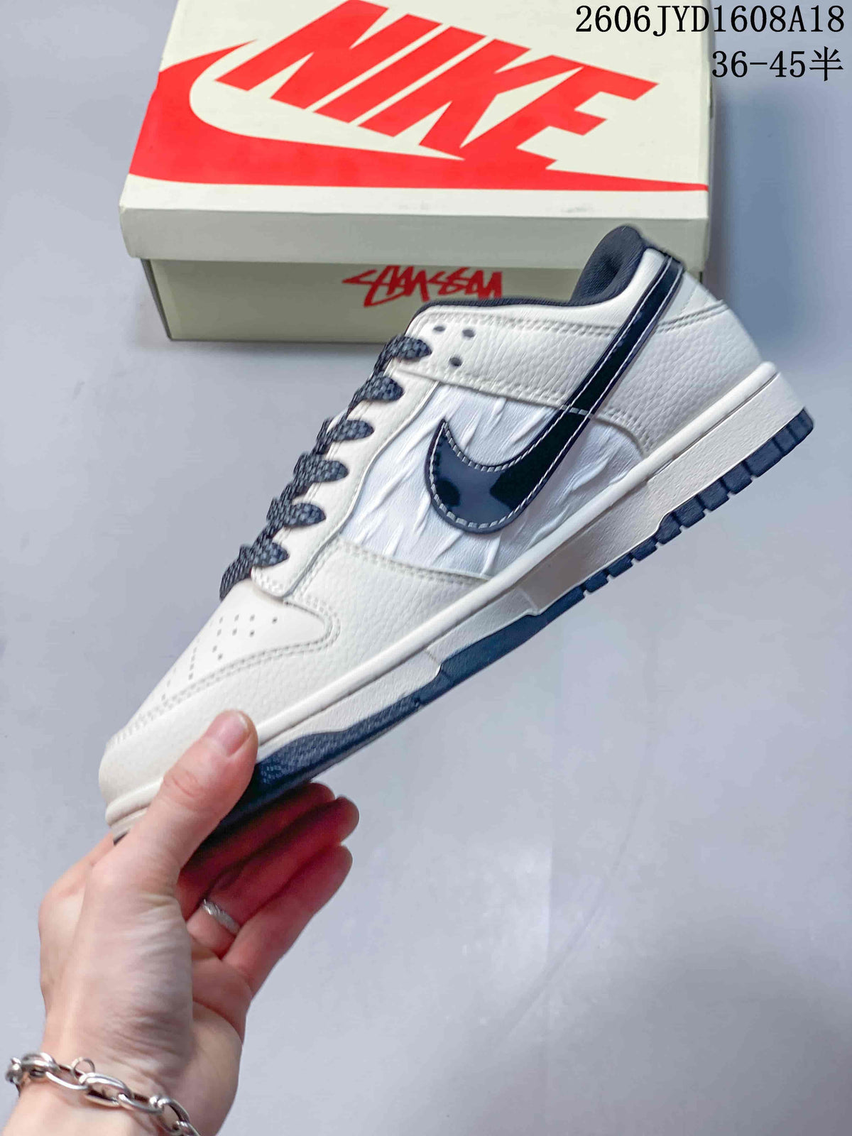 Side view of a white and navy low-top sneaker with a dark Swoosh