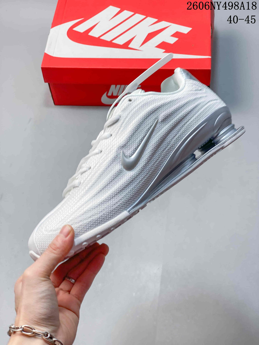 Side view of a white and silver Nike Shox TL sneaker with textured upper and heel columns