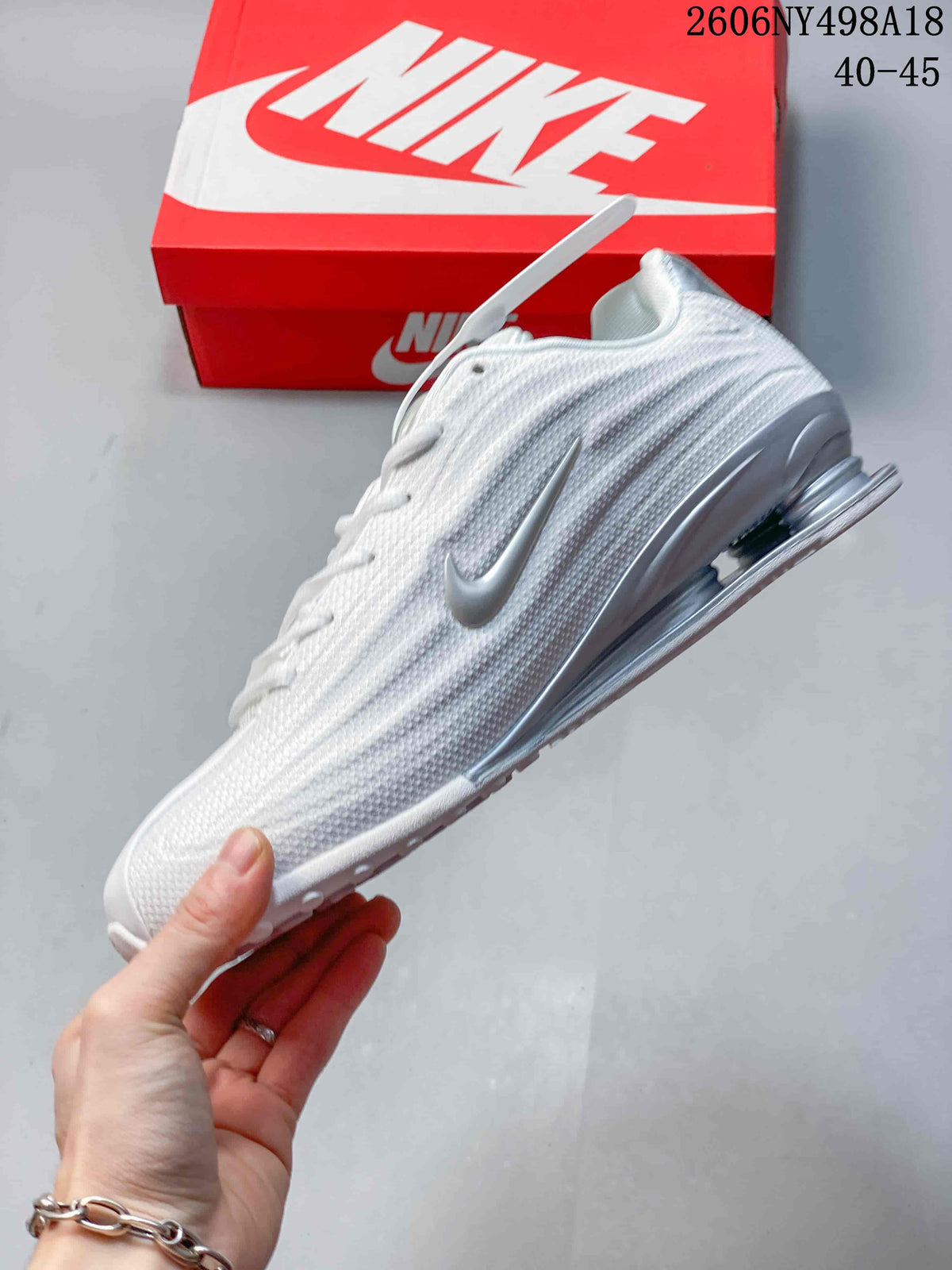Side view of a white and silver Nike Shox TL sneaker with textured upper and heel columns