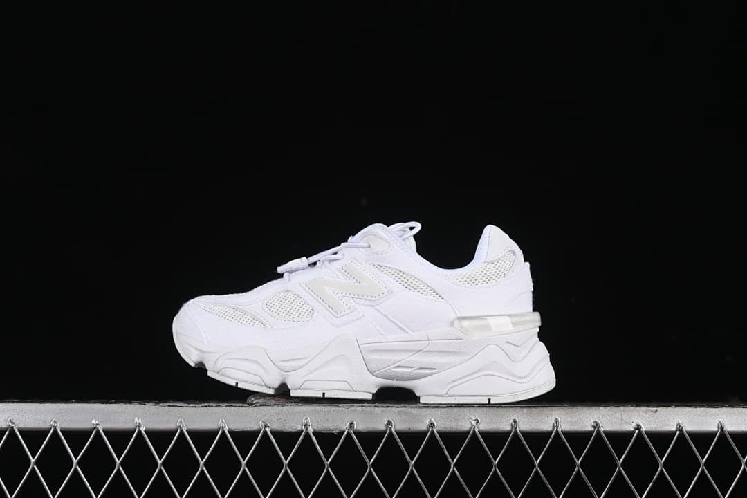 White New Balance sneaker shown in side profile against a dark background.