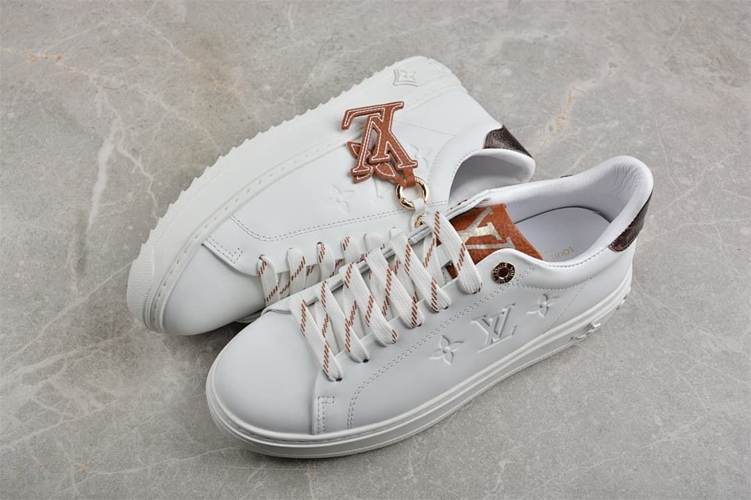 Pair of white low-top platform sneakers with brown accents and decorative charm