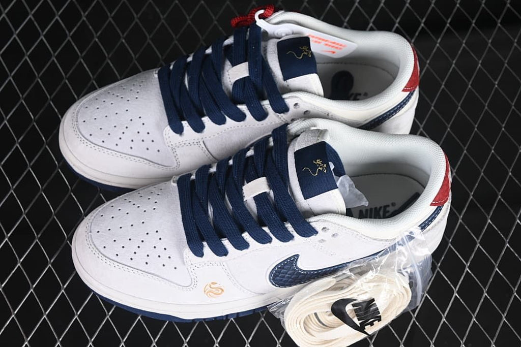 Pair of white low-top sneakers with navy laces, red accents, and an additional lace