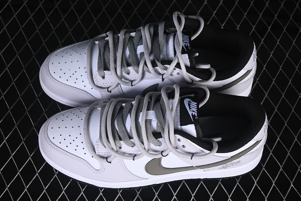 Pair of white and gray Nike SB Dunk Low sneakers shown from above, with gray laces and black collar lining