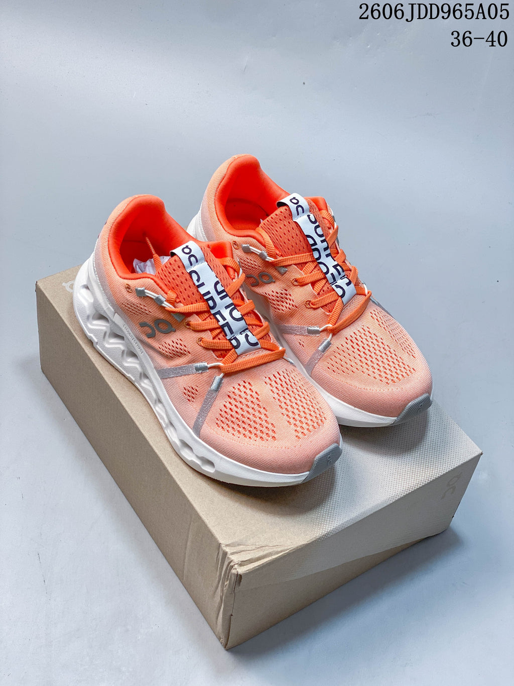 Pair of coral-pink On Cloudsurfer Trail shoes with orange laces and white soles