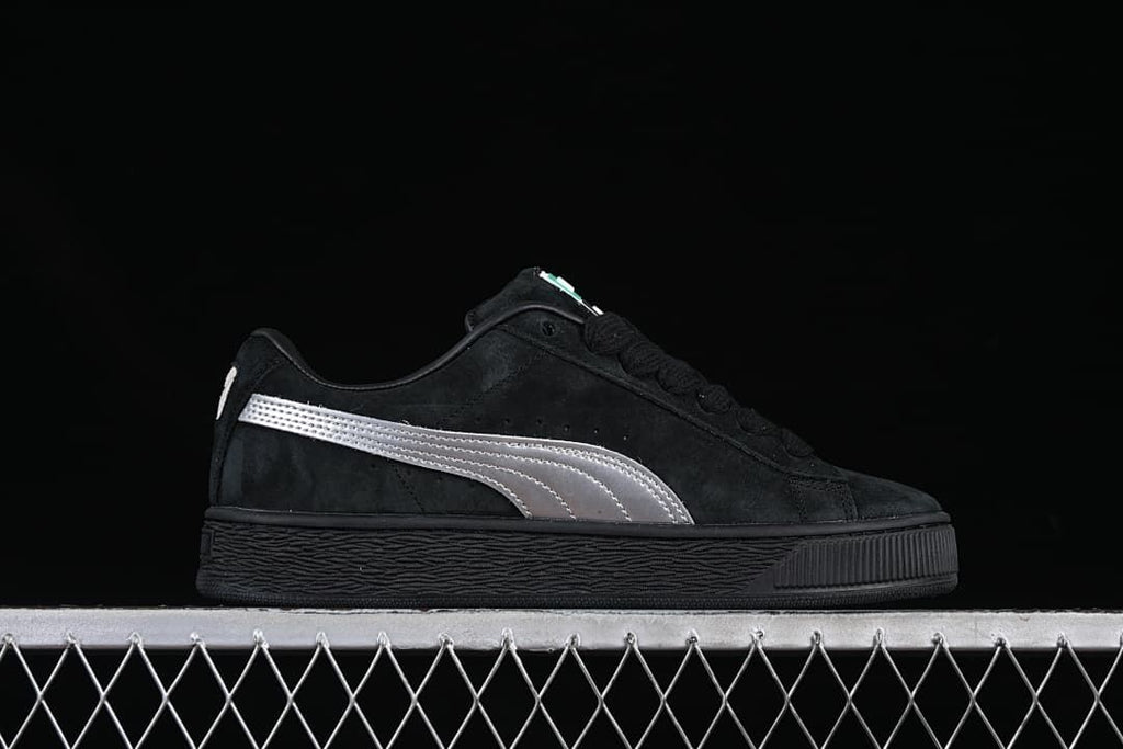 Side profile of a black sneaker with a silver stripe and textured sole.