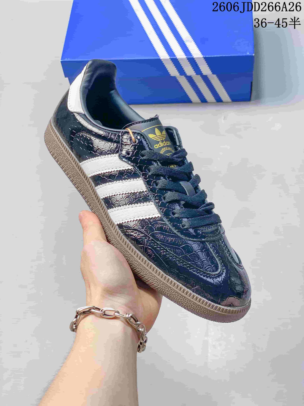 Angled view of a dark embossed-pattern Adidas Samba sneaker with white stripes and gum-tone outsole.