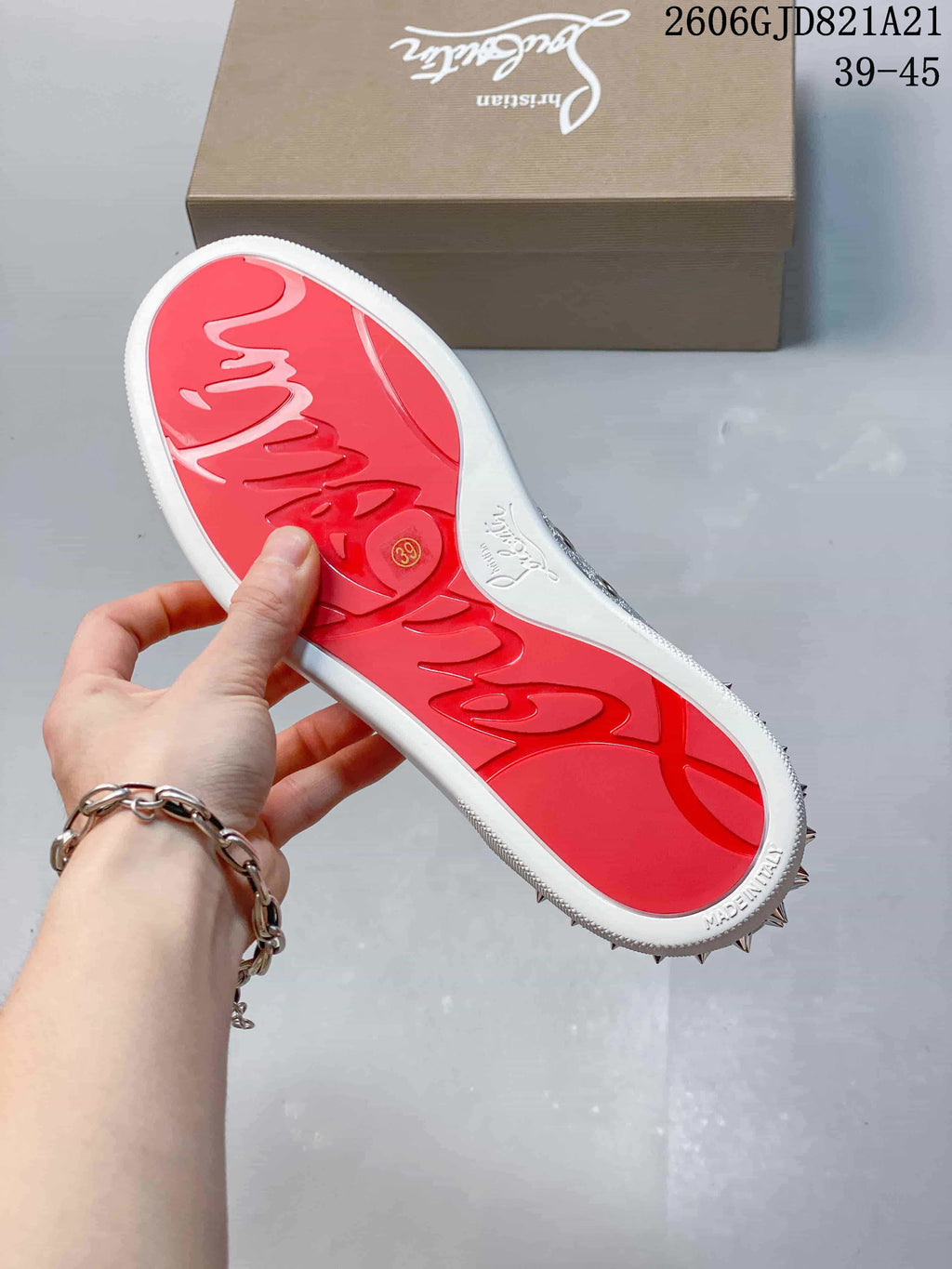 Red outsole of a silver studded sneaker, with size 39 visible