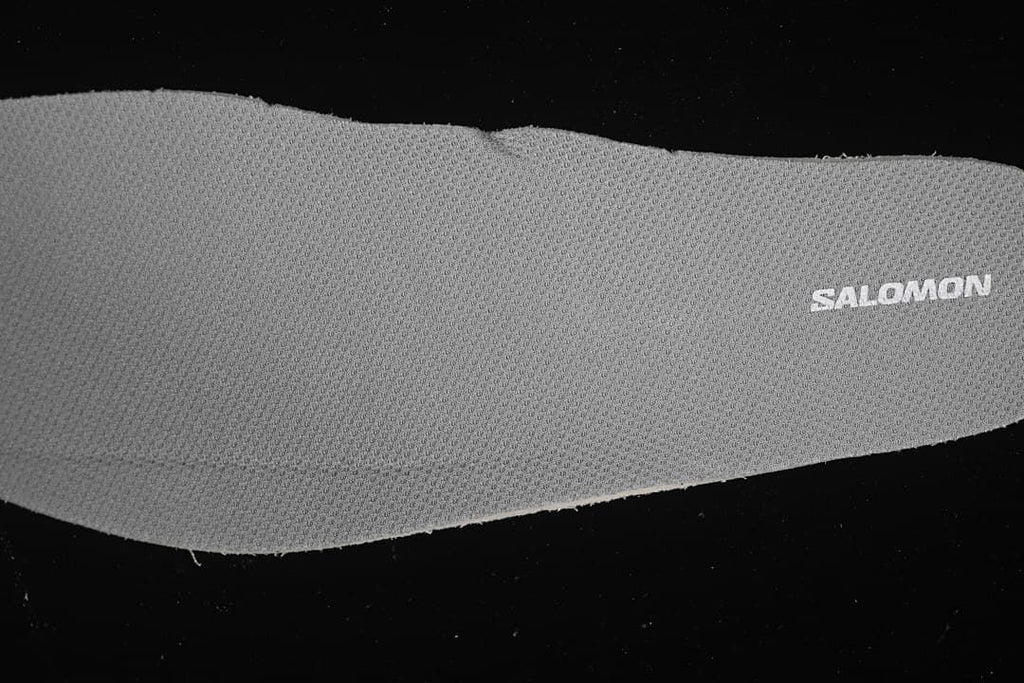 Close-up of a gray textured shoe component with Salomon branding.