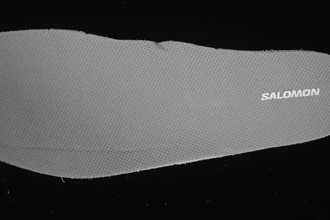 Close-up of a gray textured shoe component with Salomon branding.