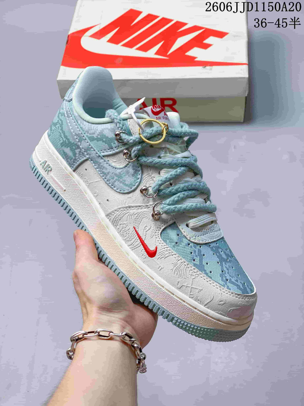 Angled side view of the sneaker with pale blue patterned panels, white detailing, and red accent