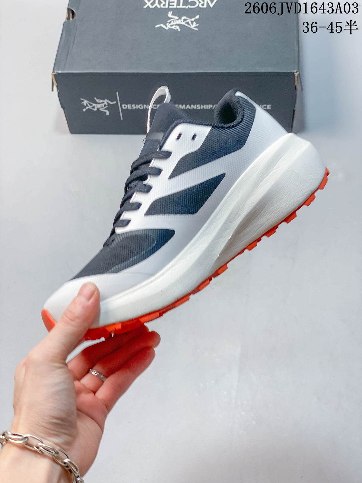 Side view of the navy and white low-top shoe with a thick white midsole and orange outsole.