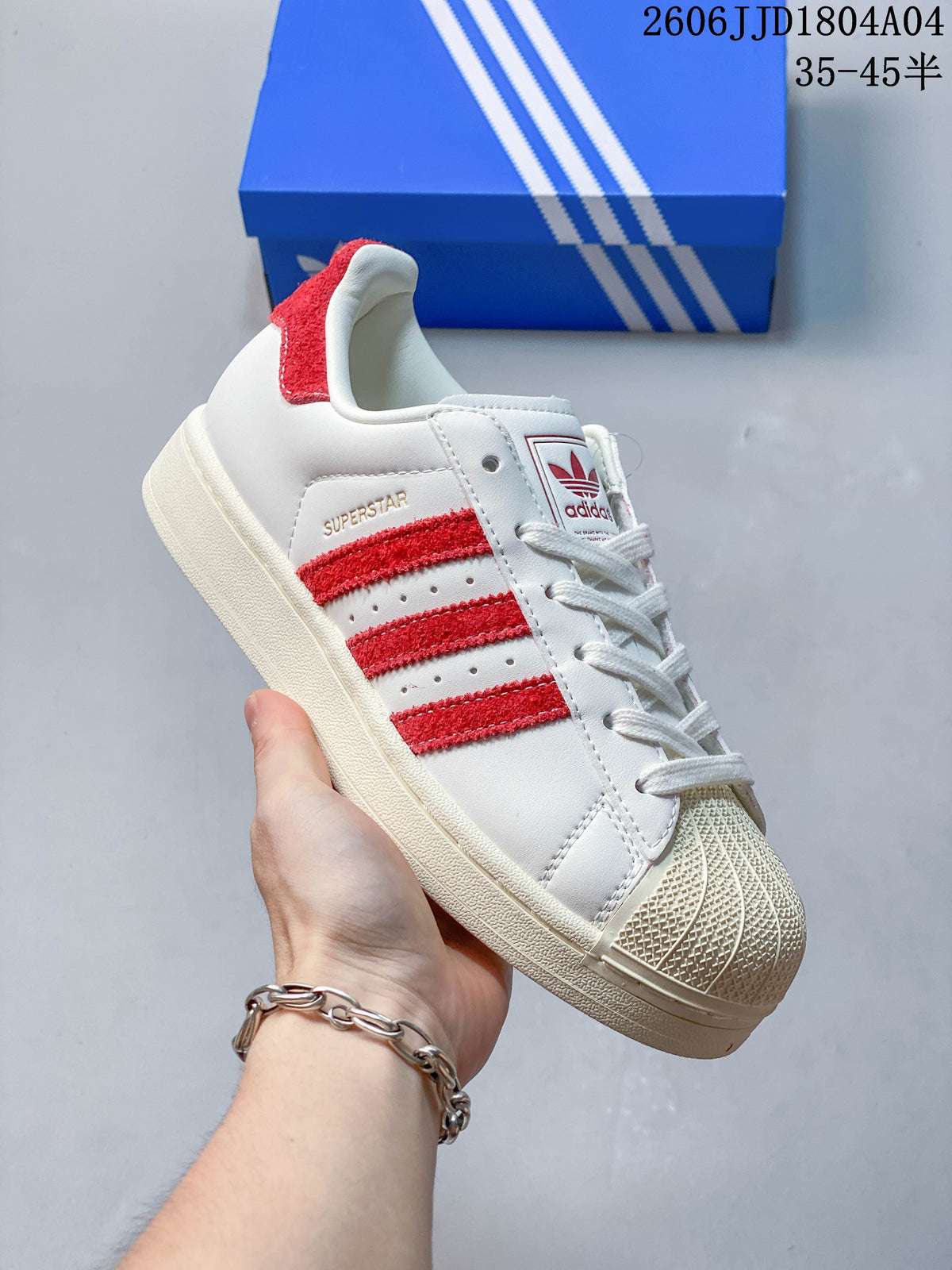 Angled close-up of the white sneaker with red stripes, shell toe, and padded collar.