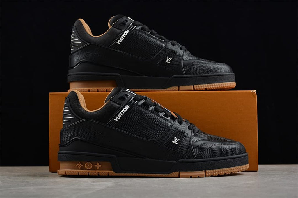 Two black low-top sneakers displayed on a box