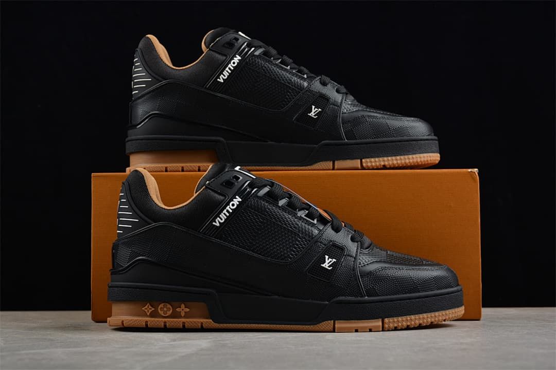 Two black low-top sneakers displayed on a box