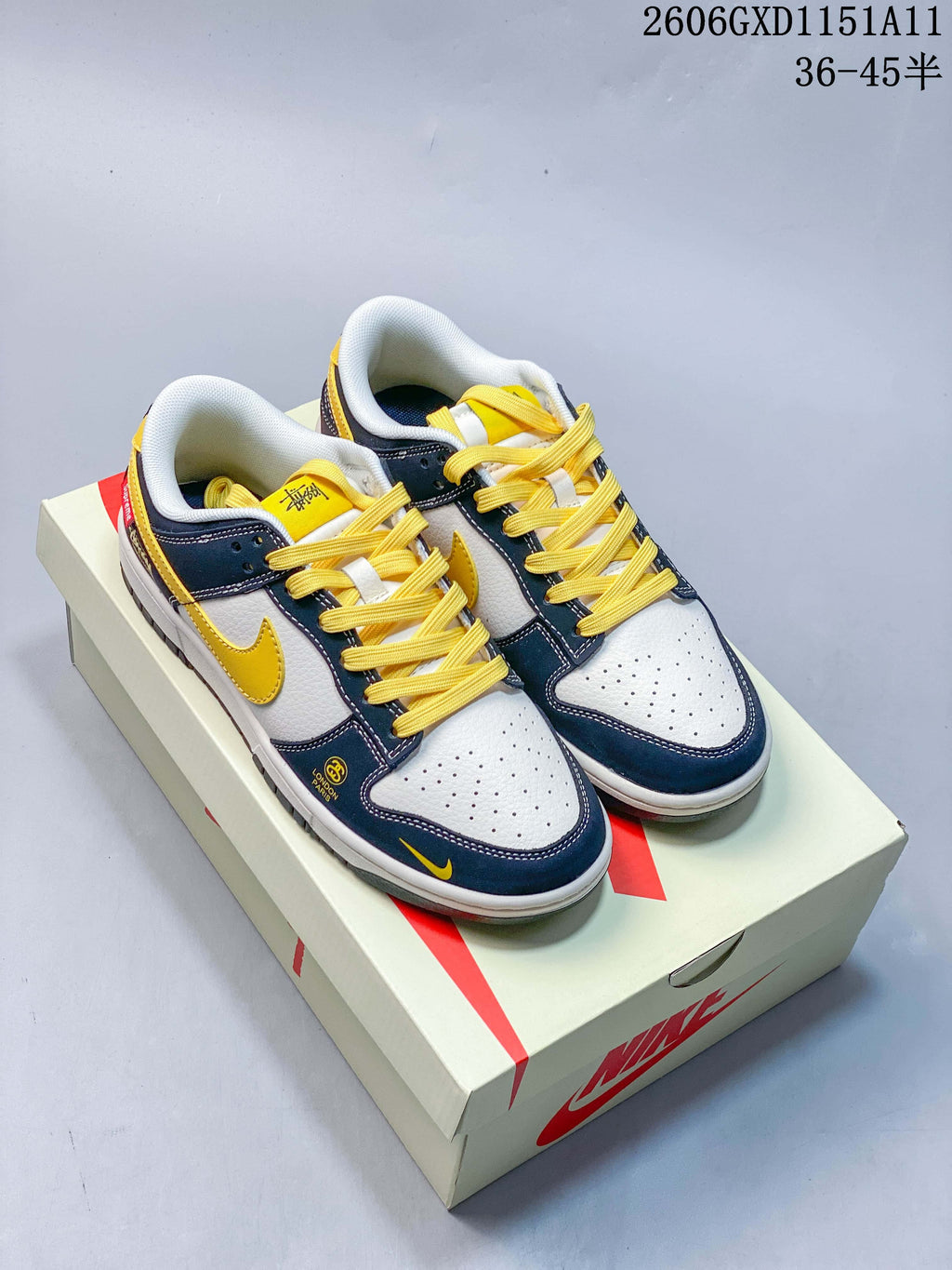 Pair of navy, off-white and yellow Nike Dunk Low sneakers on a shoe box