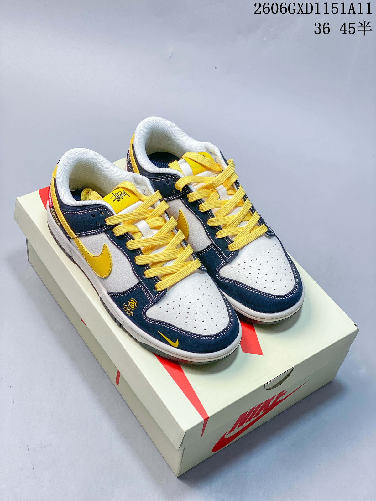 Pair of navy, off-white and yellow Nike Dunk Low sneakers on a shoe box