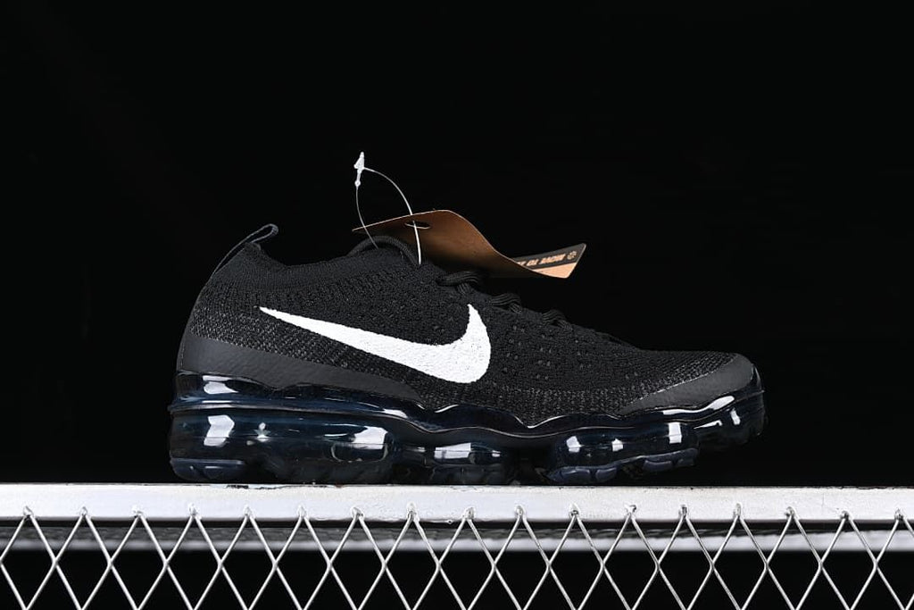 Side profile of the black sneaker with a white Swoosh and full-length visible air-cushioned sole.