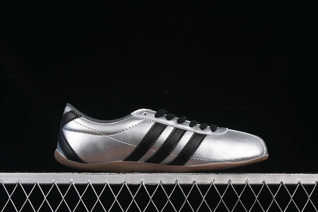 Side profile highlighting the silver upper, black stripes, and gum outsole