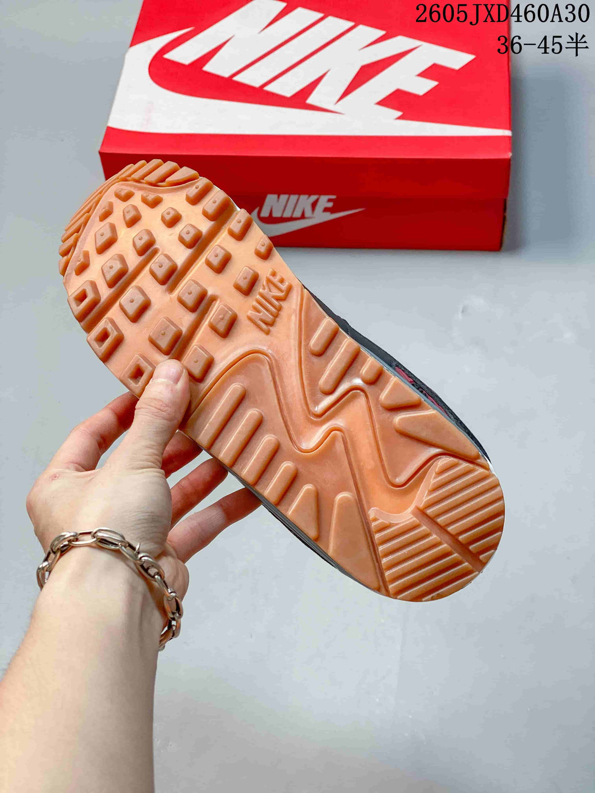Gum-colored outsole of a Nike Air Max 90 sneaker, with a shoebox in the background.