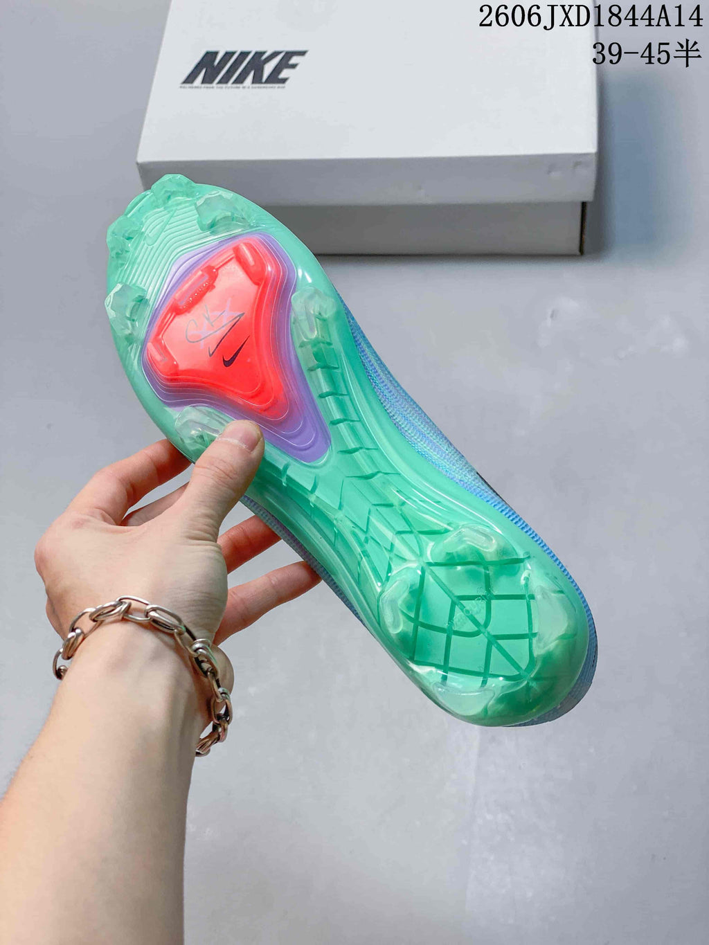 View of the translucent green studded outsole with a coral-colored central plate.