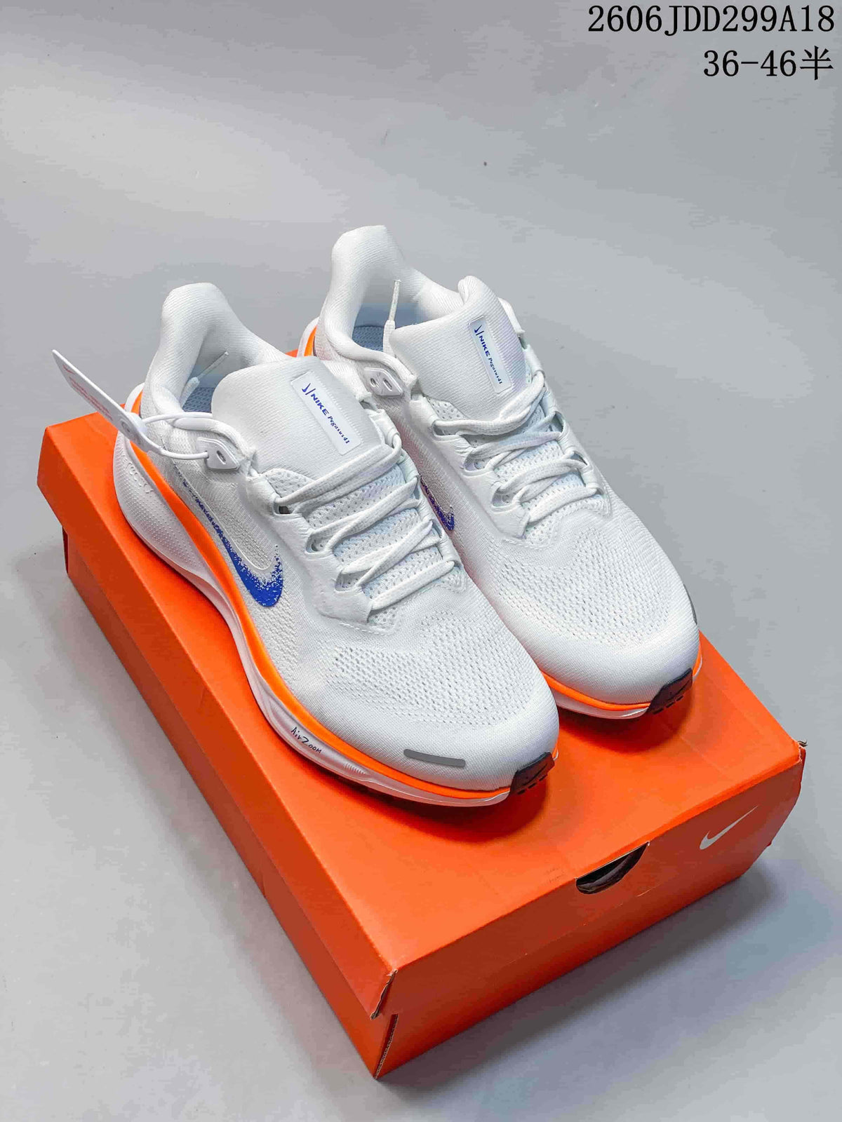 Pair of white Nike Pegasus 41 running shoes with blue Swooshes and orange accents on an orange shoe box.
