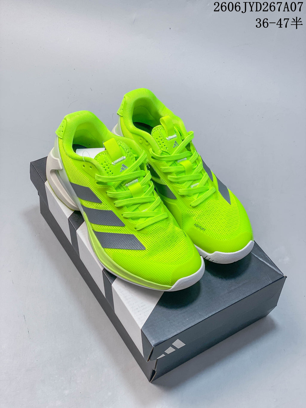Pair of bright yellow adidas Adizero tennis shoes with gray stripes, shown from above.