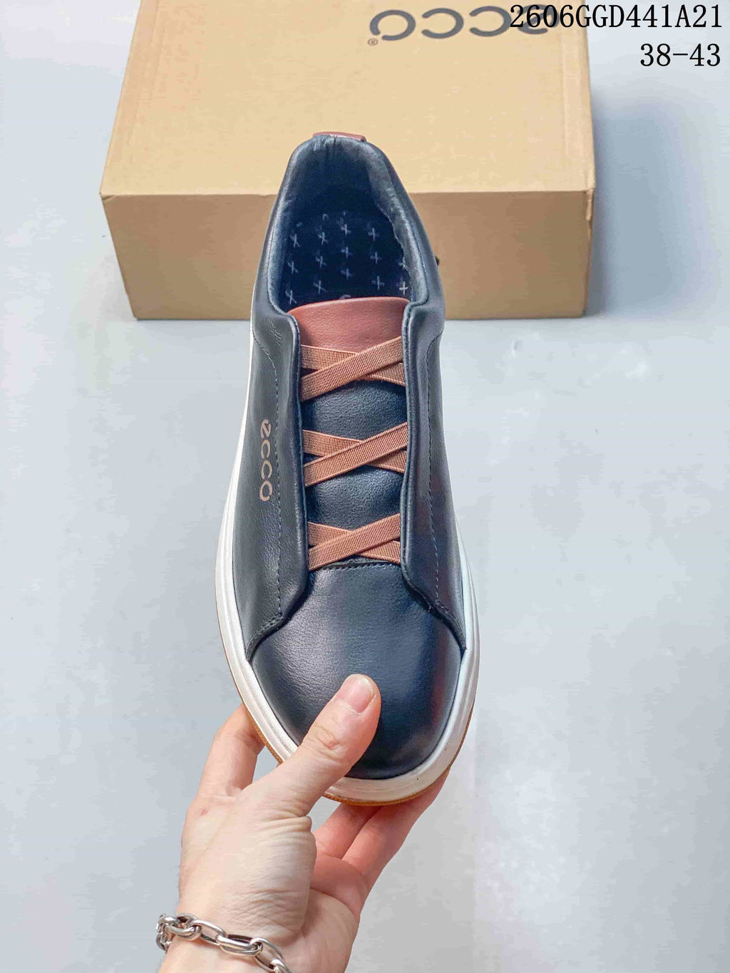 Top view of a navy sneaker with brown elastic cross-straps and a patterned insole.