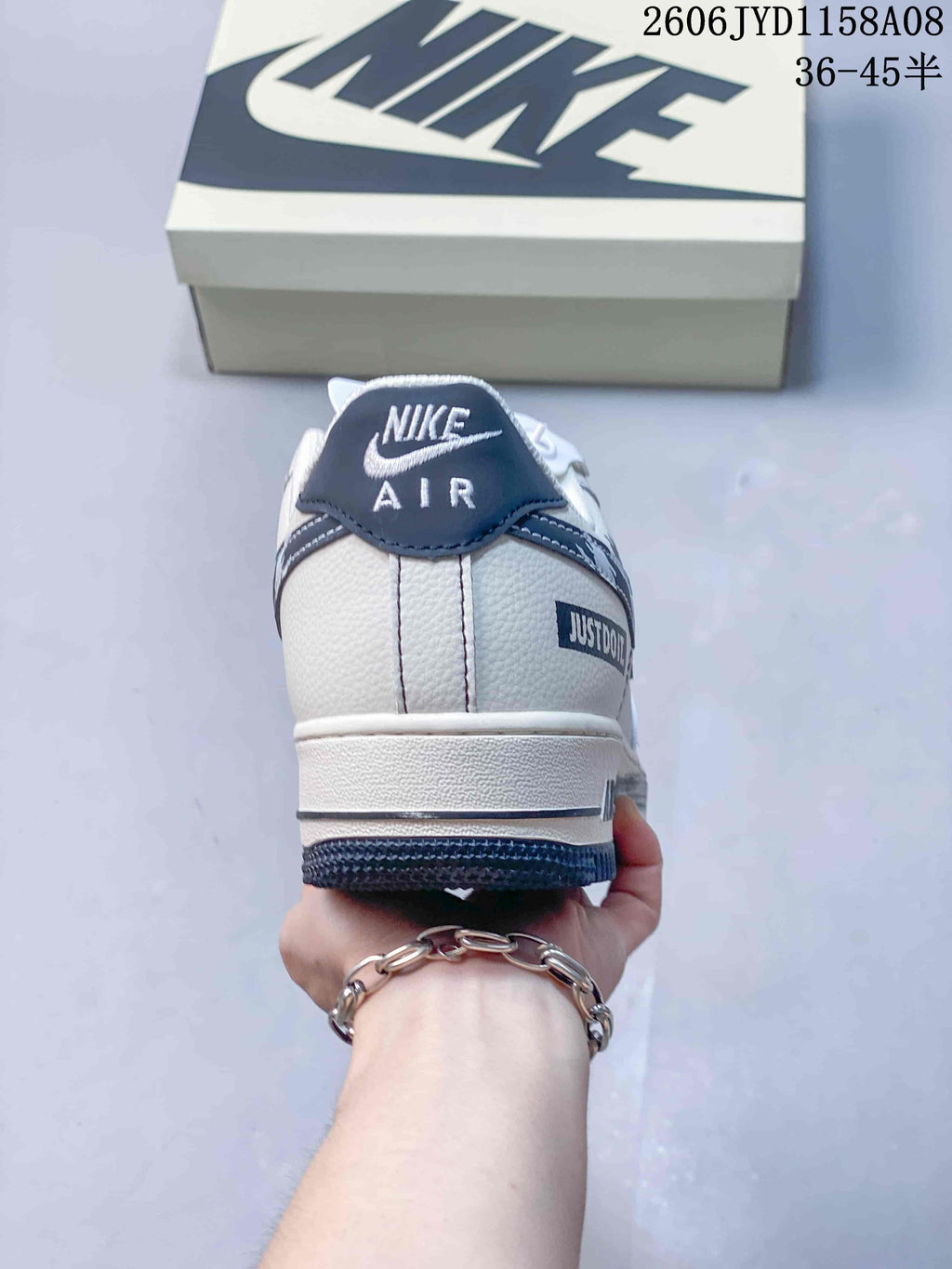 Rear view of the white sneaker with navy heel tab and decorative heel detail.